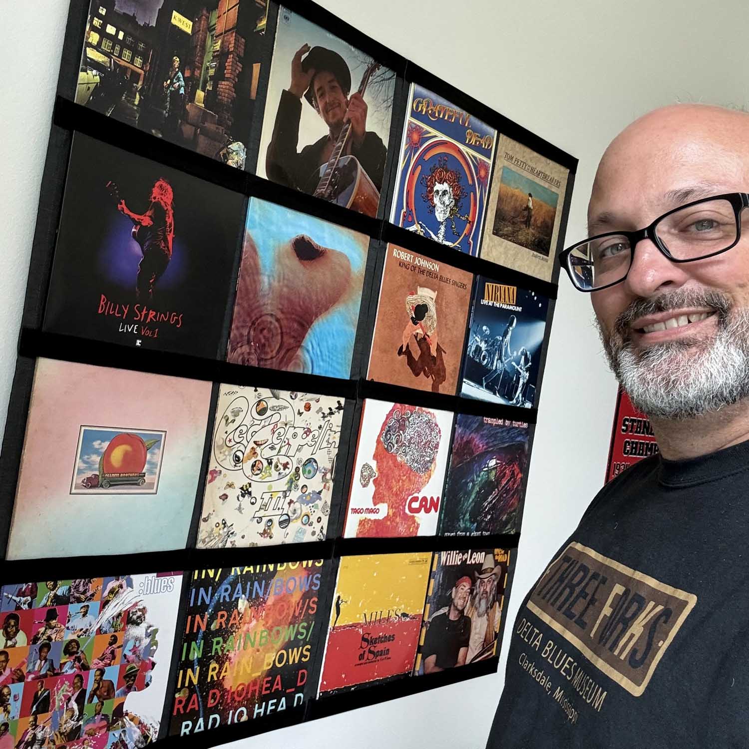 Collector smiling beside a wall-mounted vinyl record display