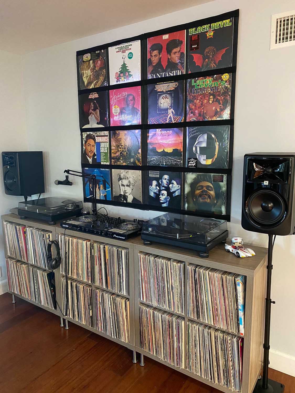 Vinyl display frames above twin turntables and a record collection