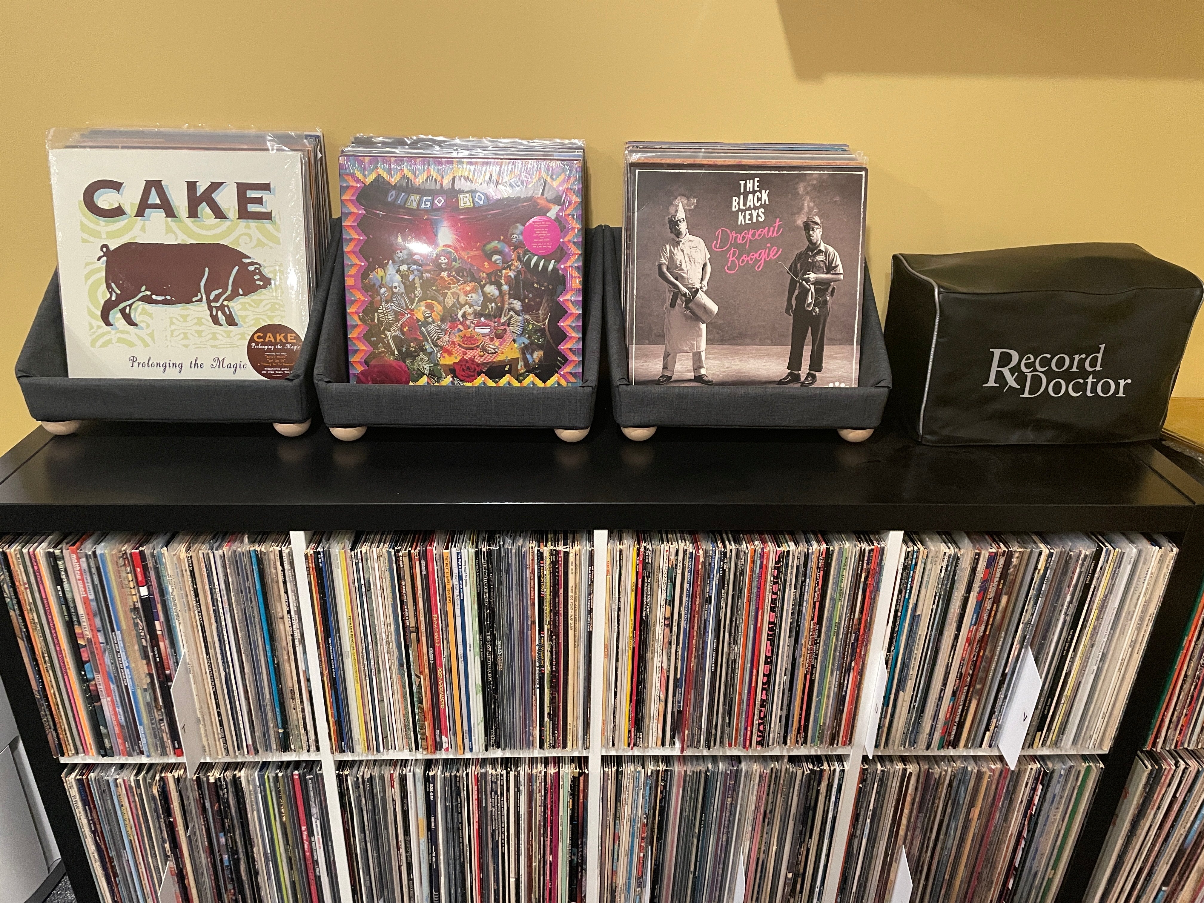 Three tabletop storage containers above shelves of vinyl records
