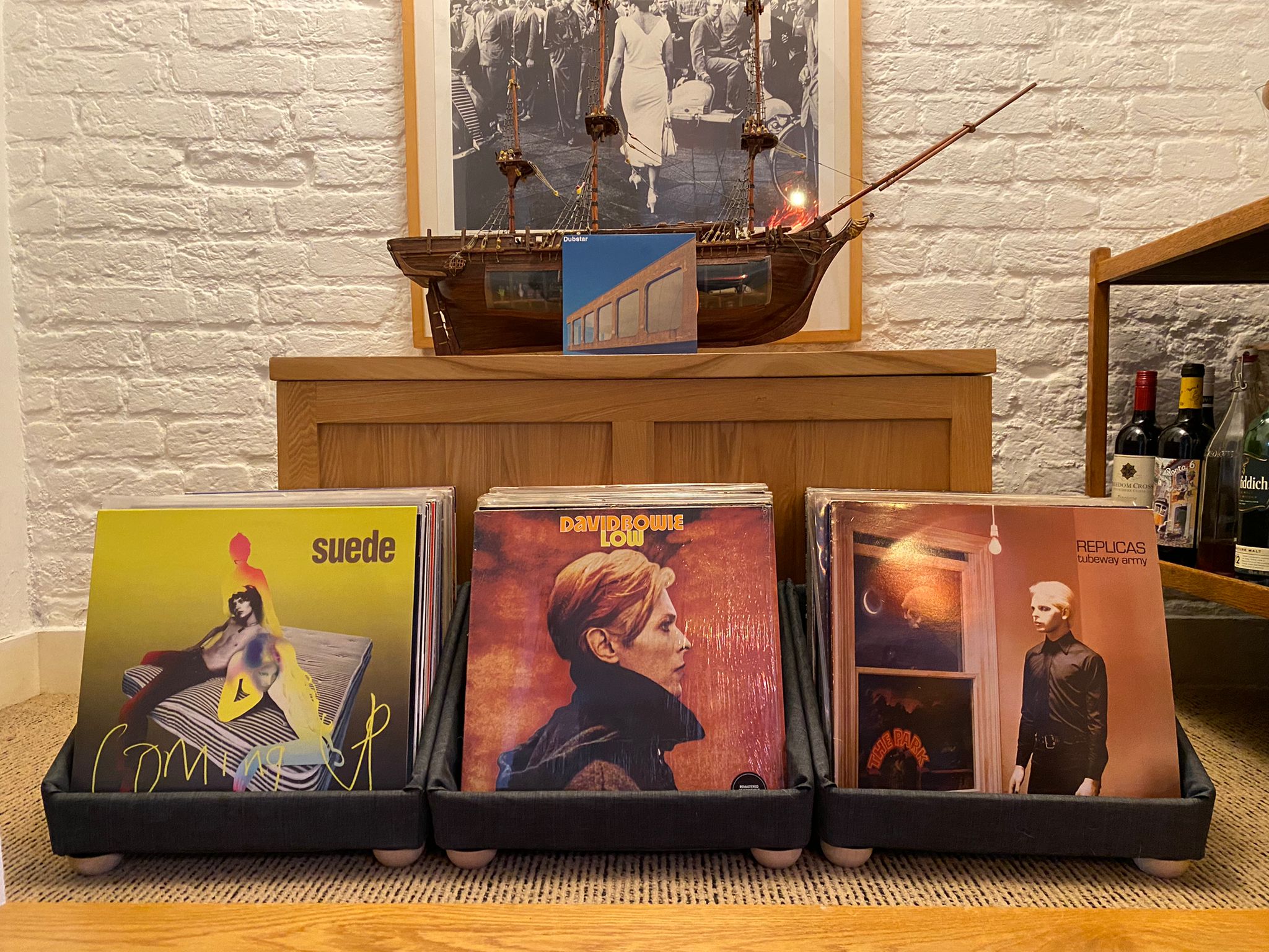 Three tabletop storage containers displaying albums in a home