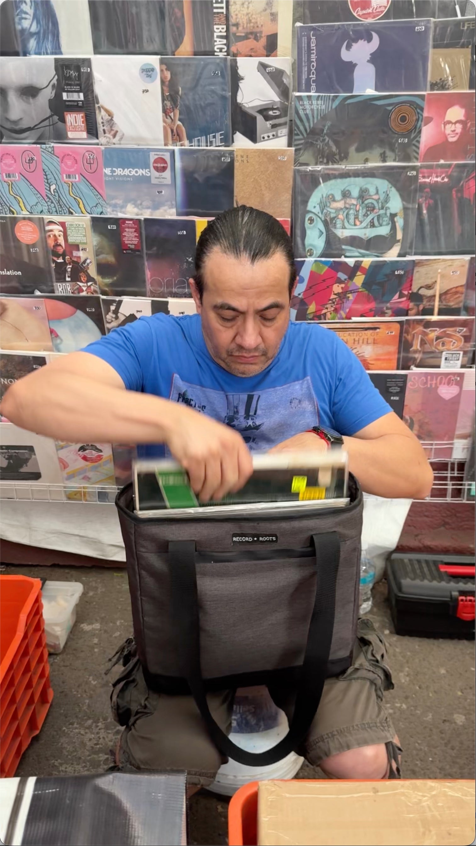 Collector packing vinyl records into a Record Roots tote bag in a record shop